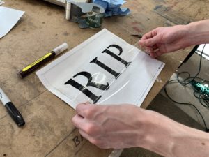 Placing clear packing tape placed over a paper stencil to make it reusable - How To Holiday