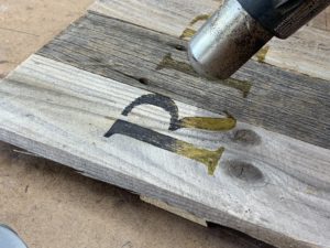 Burning pyrography marker letters on a wood halloween tombstone with a heat gun - How To Holiday