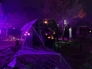 Halloween 2020 - Halloween creepy barn on path with candles and skeleton under red and green and purple lighting