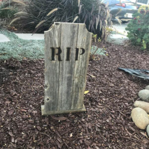 Medium Round Dog Ear Tombstone with burned RIP letters in a garden