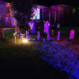 Wood tombstones mixed in with Halloween decorations in purple light